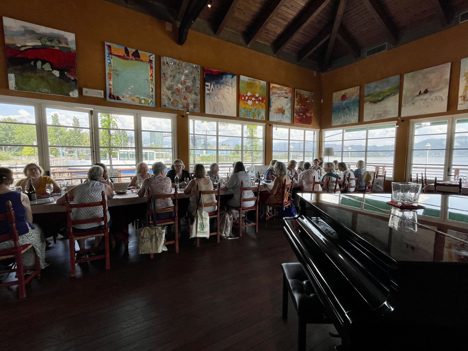 A group of people are sitting at tables in a large room with a piano
