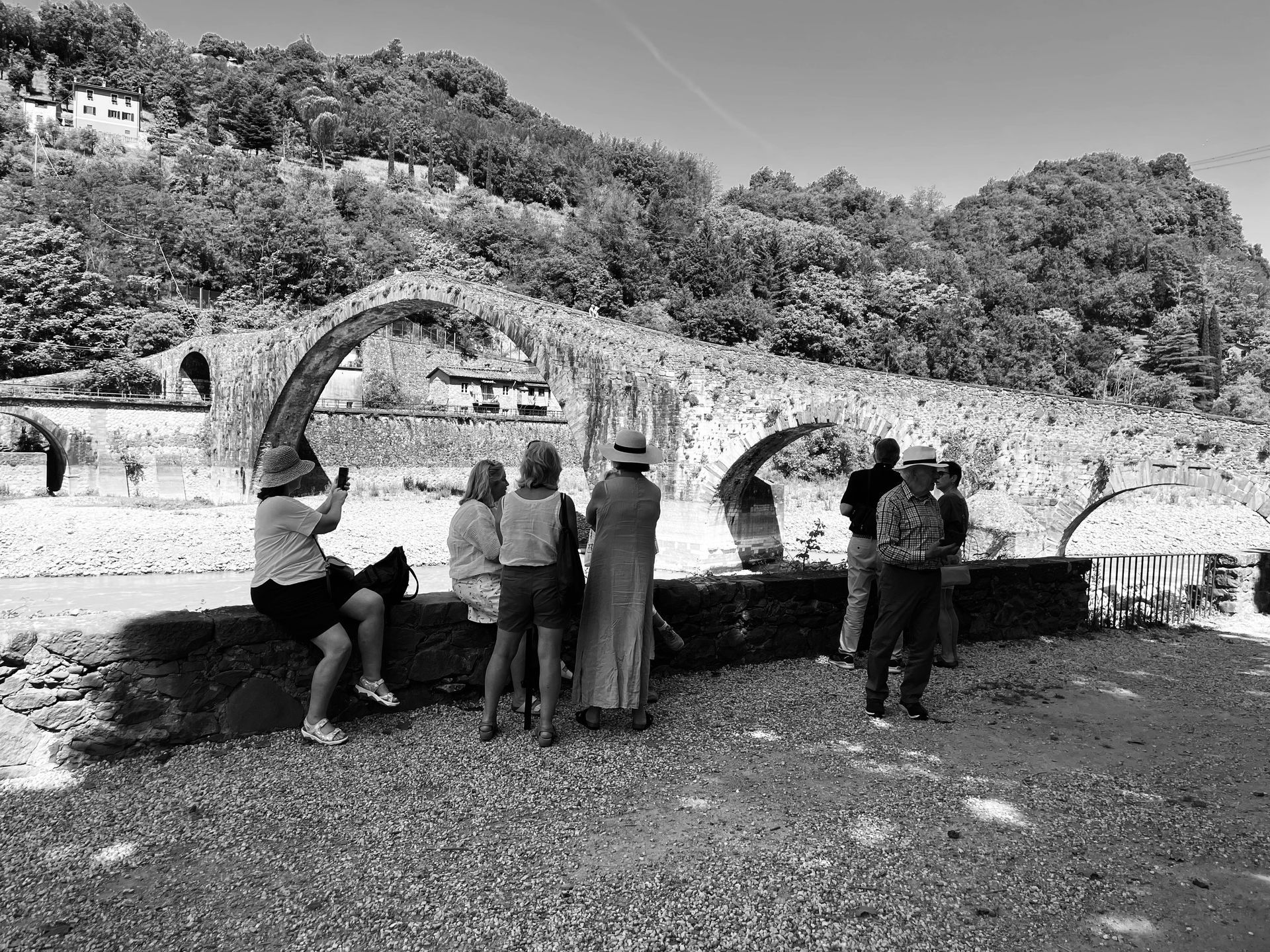 A black and white photo of a group of people looking at a bridge.