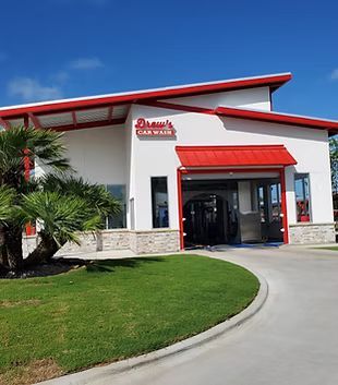 A white building with a red awning that says ' dash 's car wash ' on it