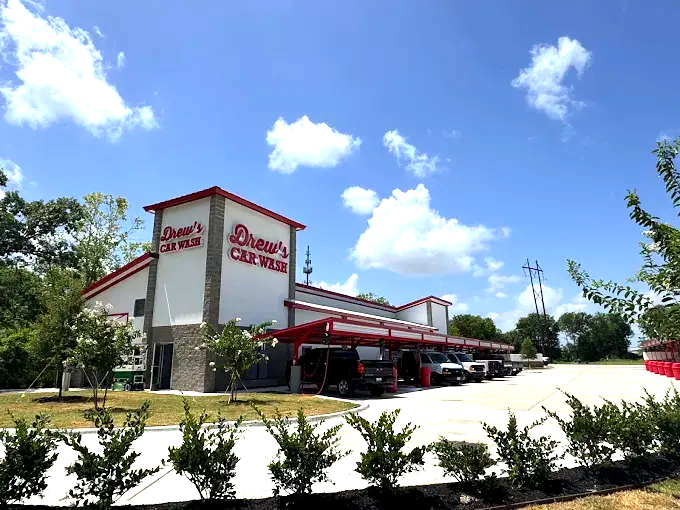 A white building with a red awning that says ' johnson 's car wash ' on it