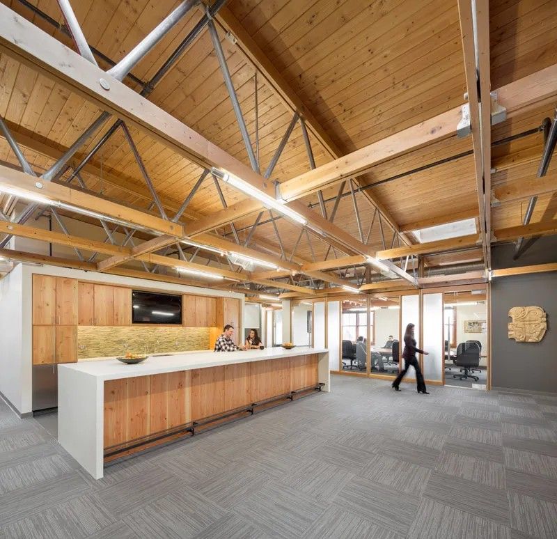 A woman is walking in a large room with a wooden ceiling