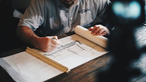 A man is sitting at a table looking at a blueprint.