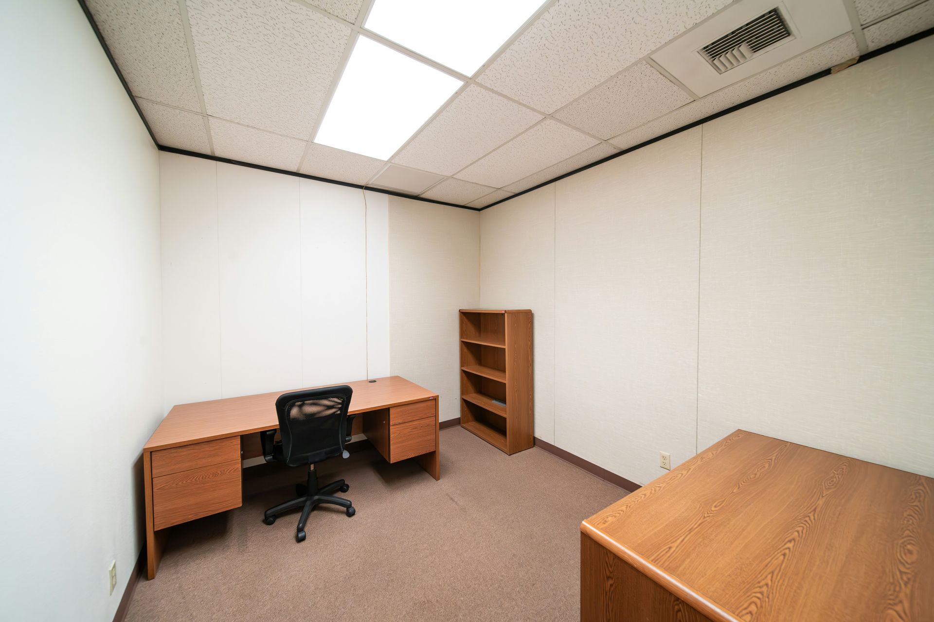And empty office with wooden desk, bookshelf, and table ready to move along with a computer chair