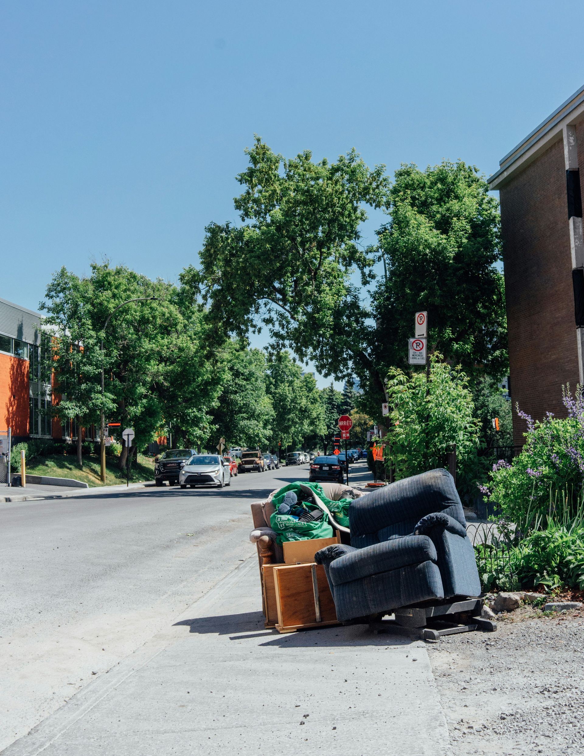 A pile of furniture sitting on a curb beside a road waiting to be hauled off