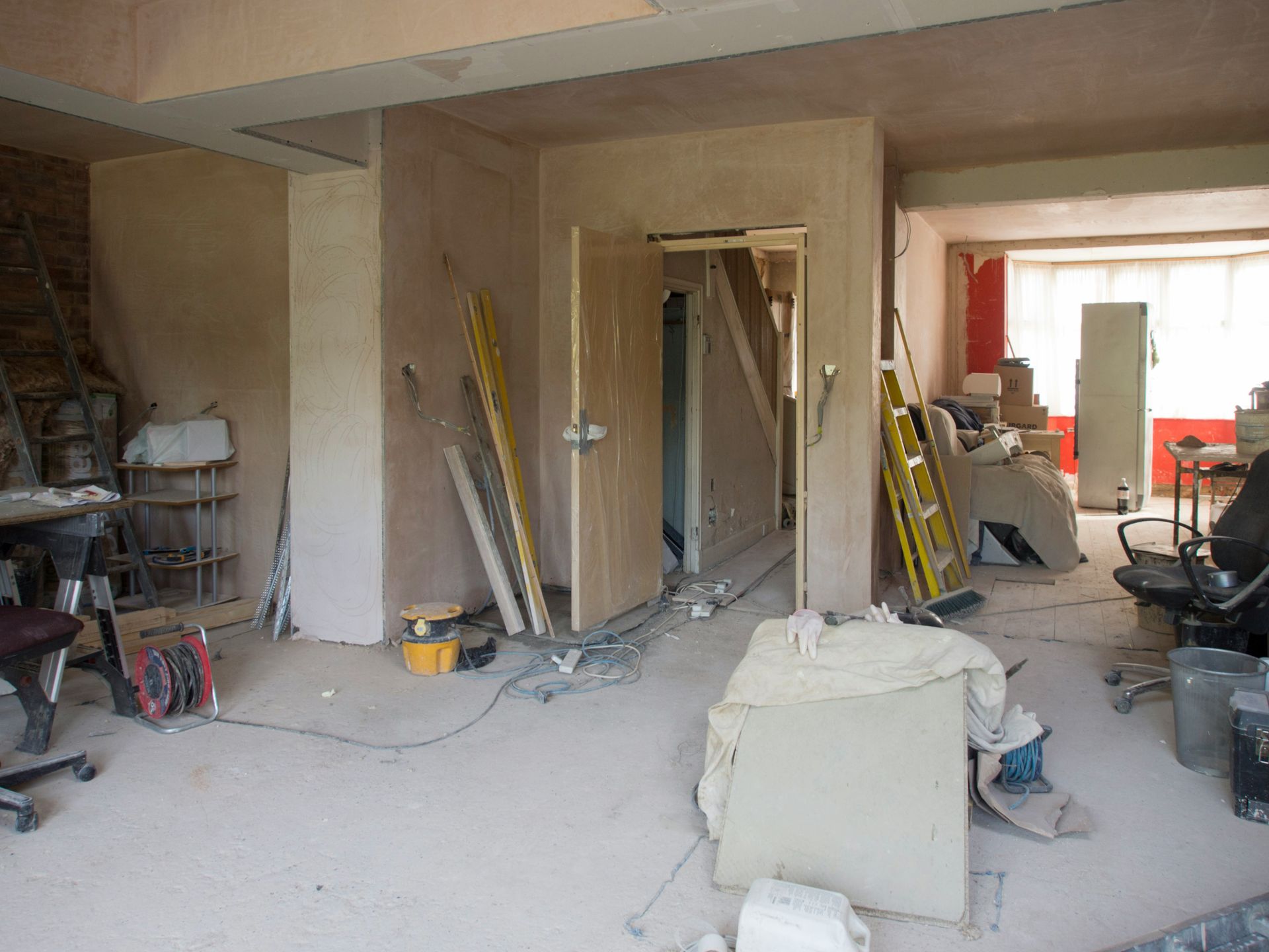 An open living room and kitchen in the process of a major renovation with tools and materials scattered around