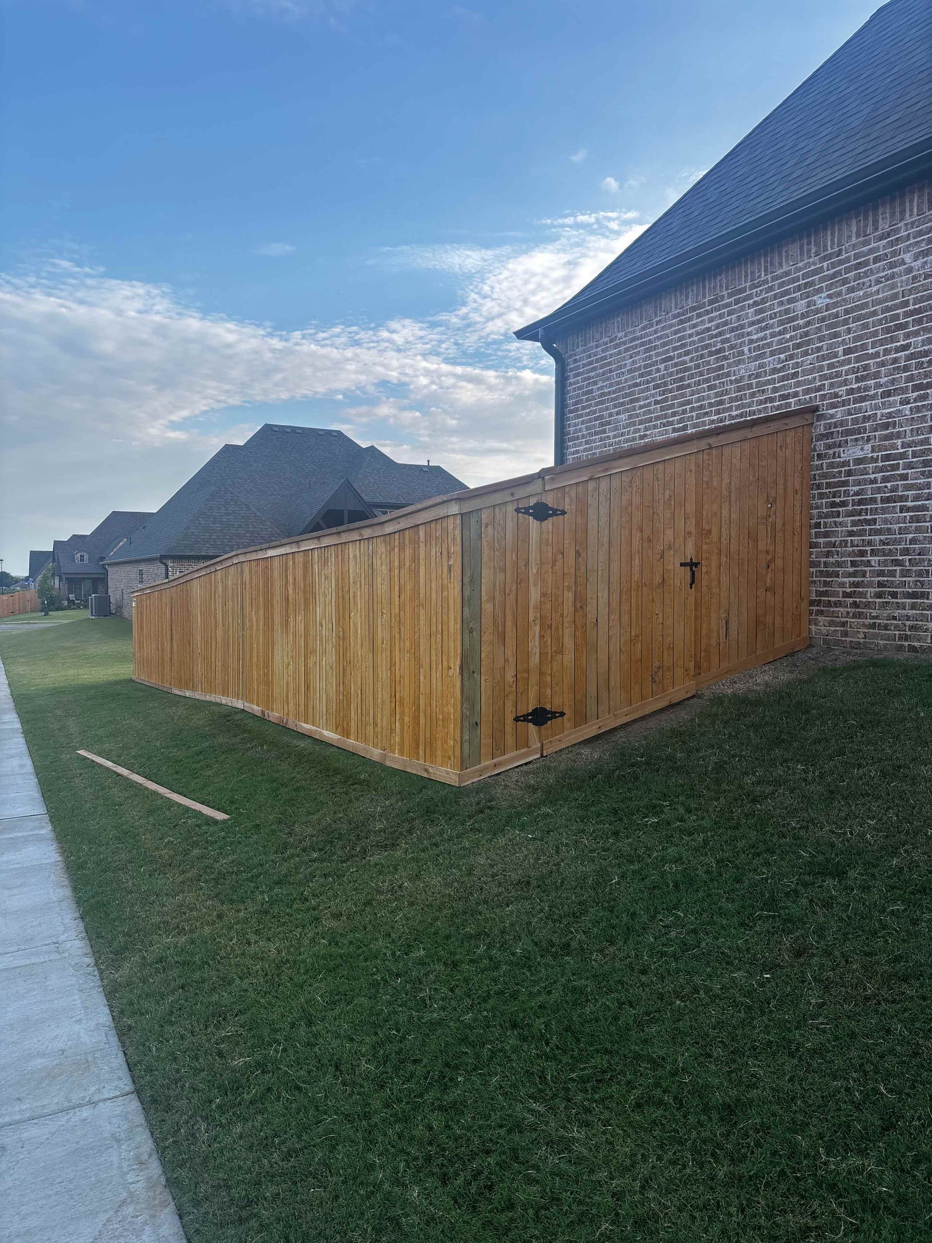 Wooden shed beside a brick house in a grassy backyard at sunset