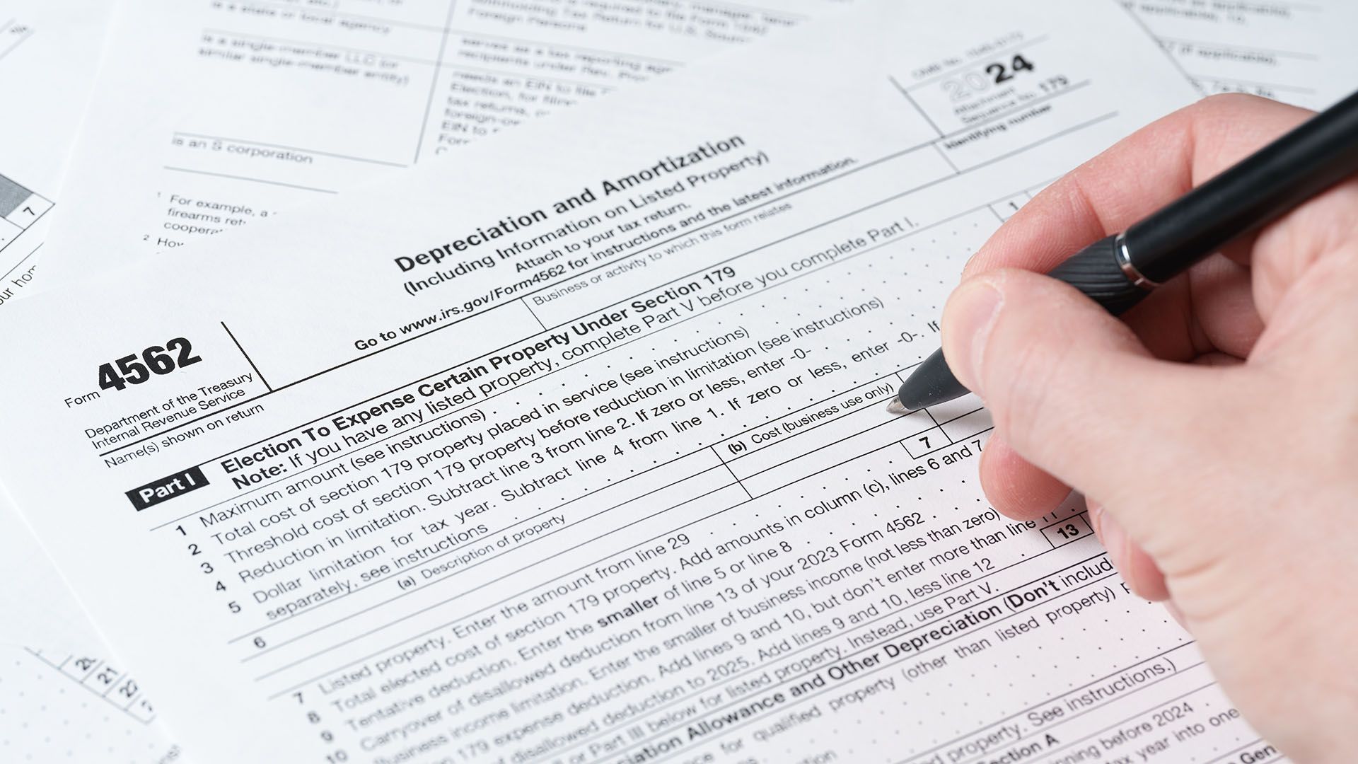 Hand completing IRS form with pen for tax depreciation paperwork and financial documentation. Hand completing IRS form with pen for tax depreciation paperwork and financial documentation.