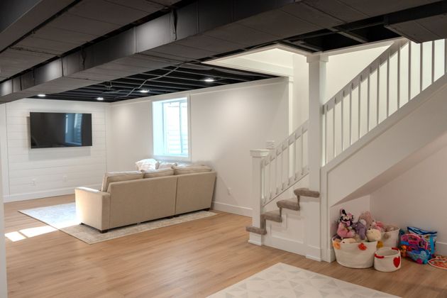 A living room with a couch and stairs in a basement.