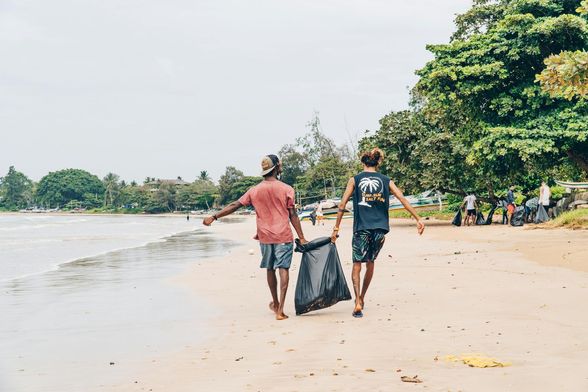 a man is carrying a bag of trash next to a garbage truck .
