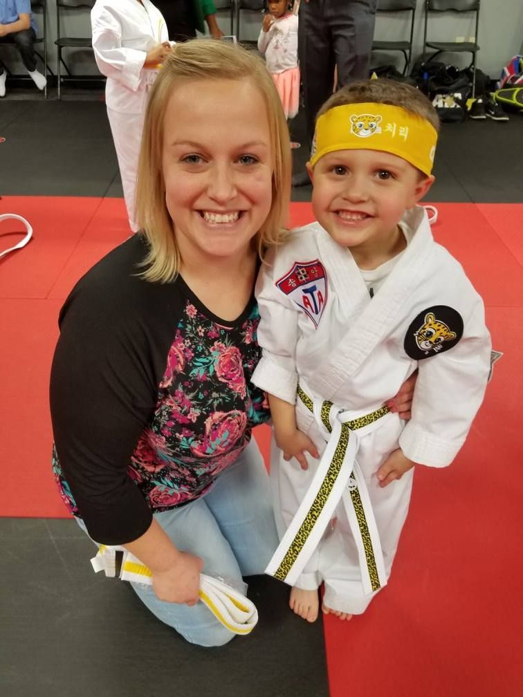 A woman is kneeling next to a young boy wearing a yellow headband