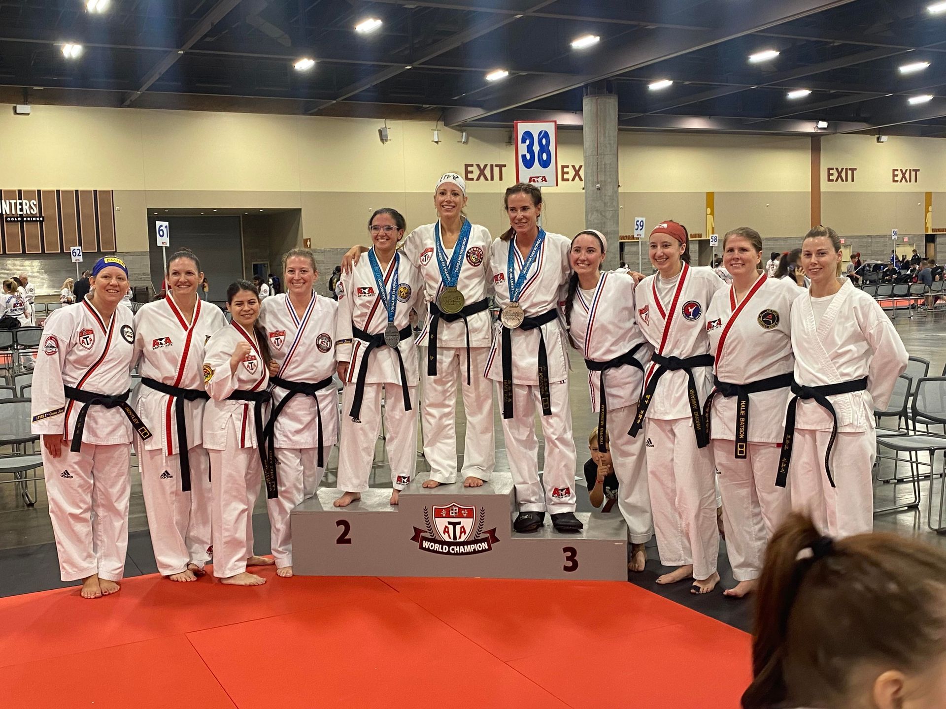 A group of women in karate uniforms are posing for a picture on a podium.