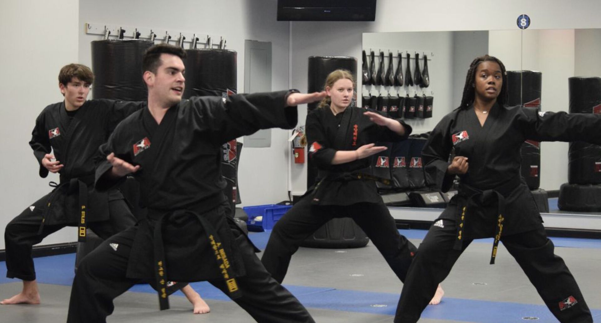 A group of people are practicing karate in a gym.