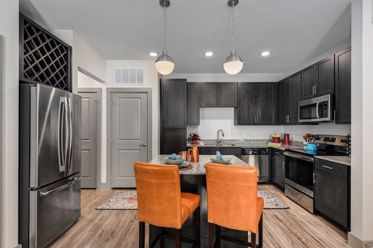 Modern kitchen in an apartment with dark cabinetry, island seating, and stainless steel appliances.