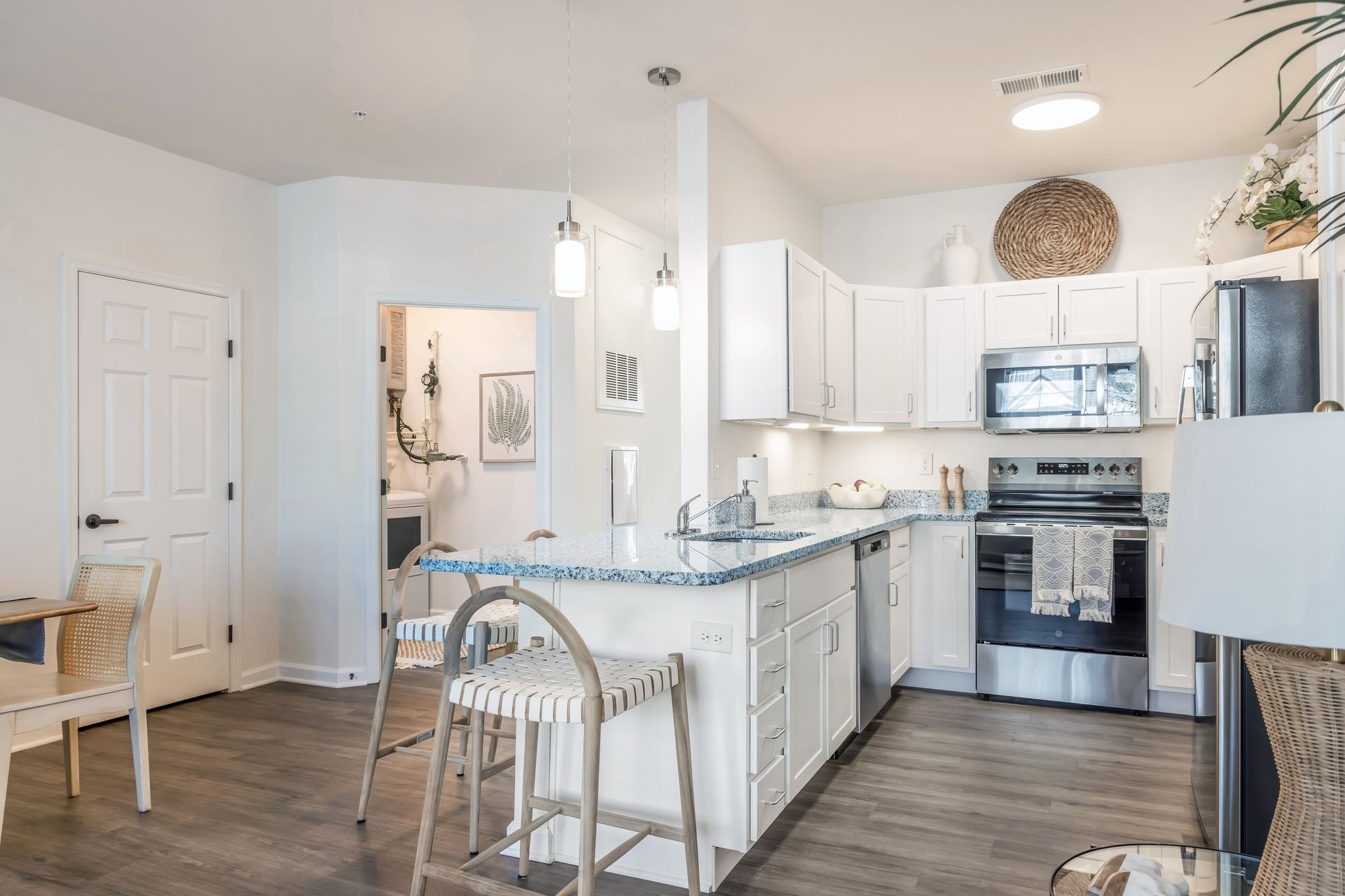 Bright white kitchen with a breakfast bar, stainless steel appliances, and wooden floors.