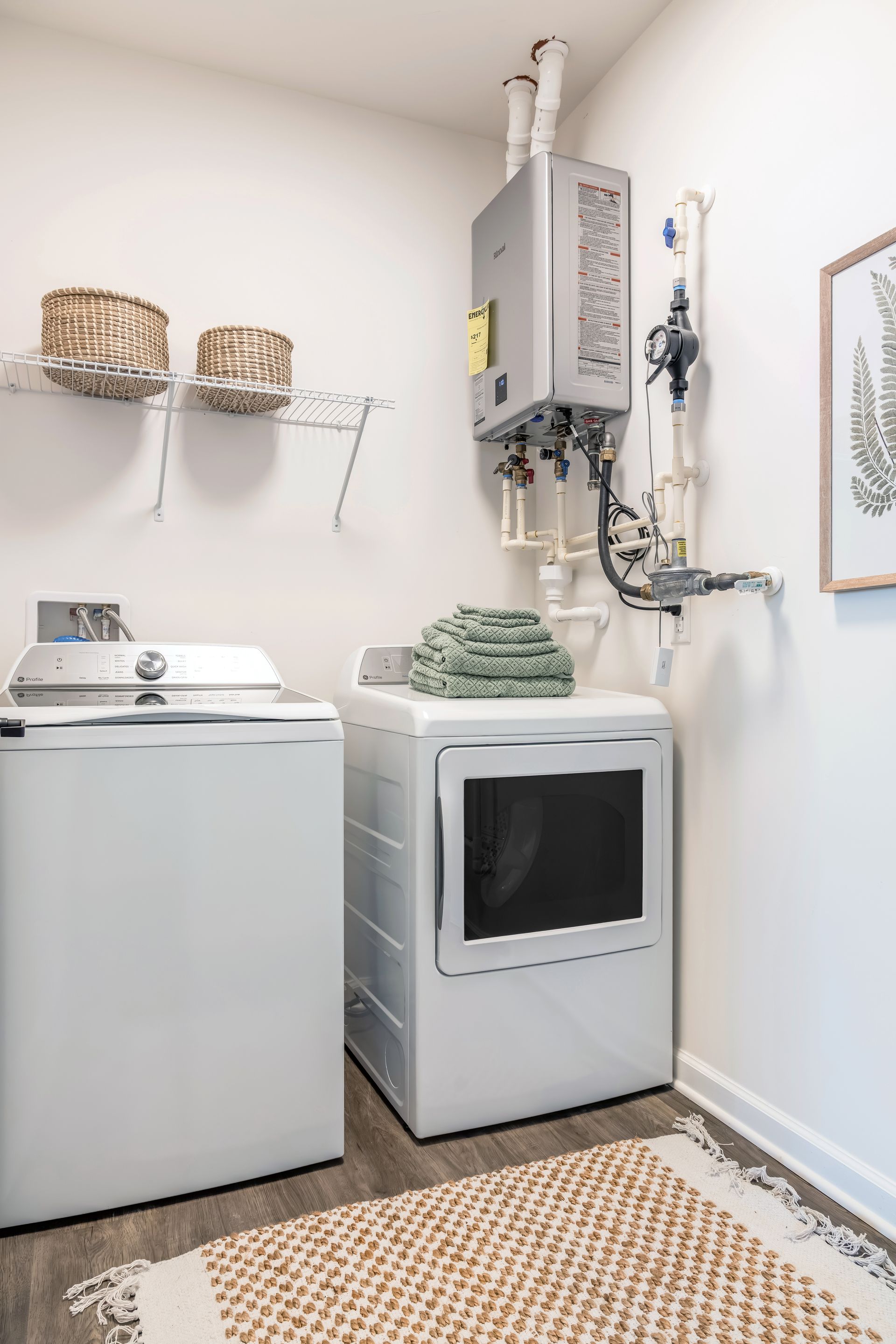 Laundry room with a washing machine, dryer, water heater, and storage baskets.