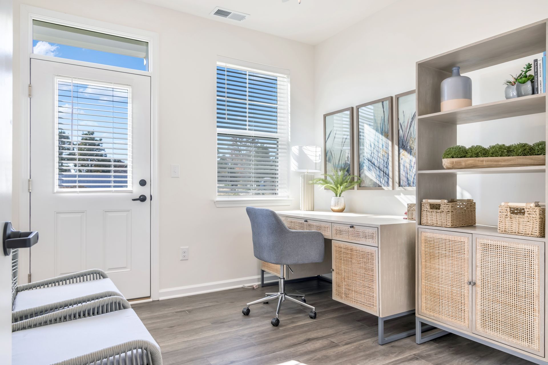Bright home office with desk, chair, and bookcase by a window and door. Light wood and gray accents.