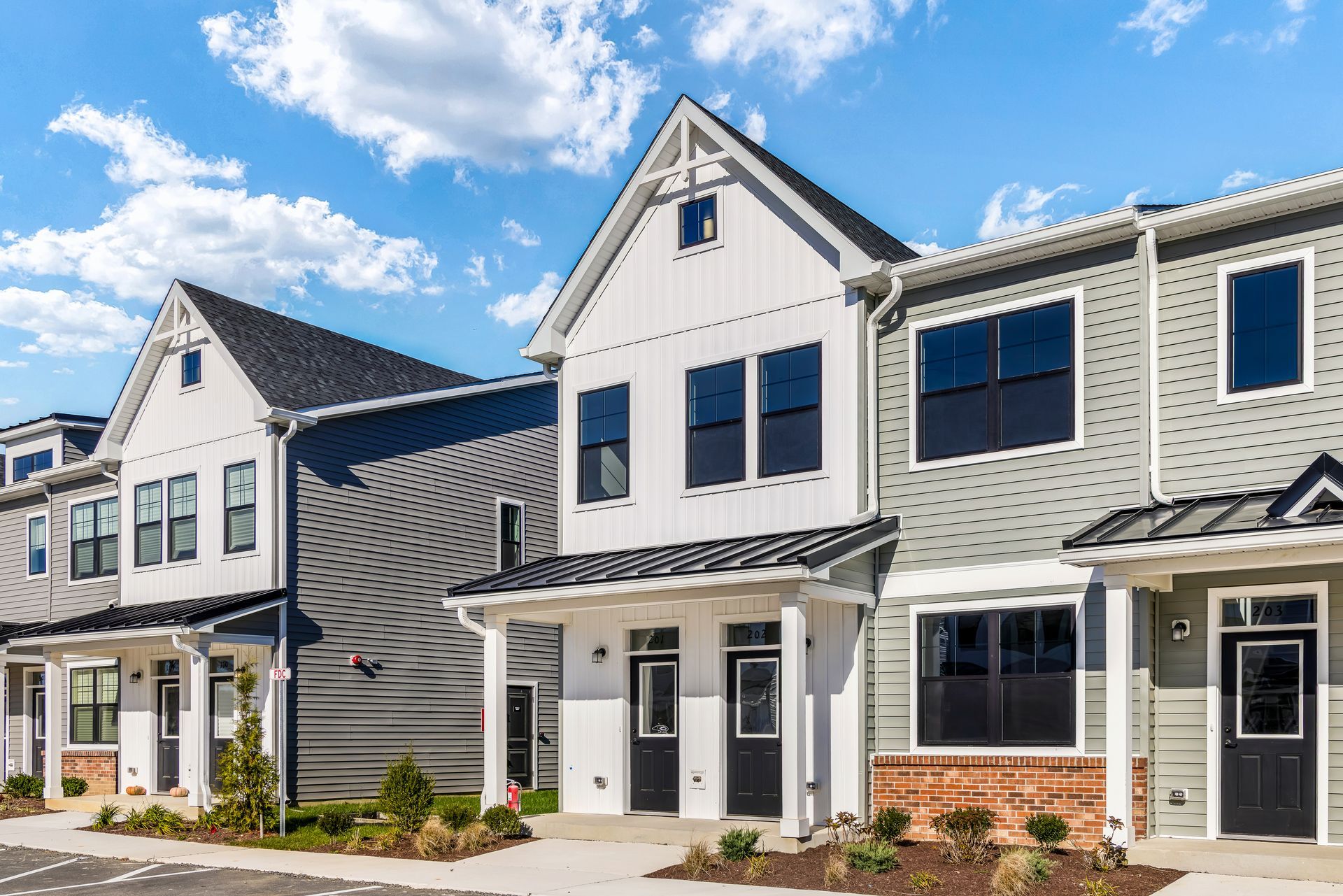 Row of modern townhouses with white and gray siding under a blue sky.