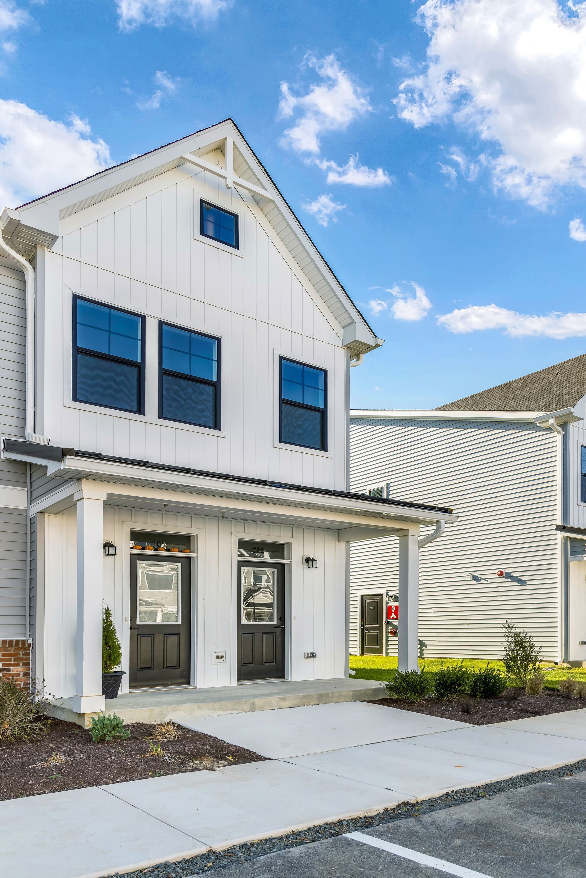 White townhouses with black doors and windows against a blue sky.