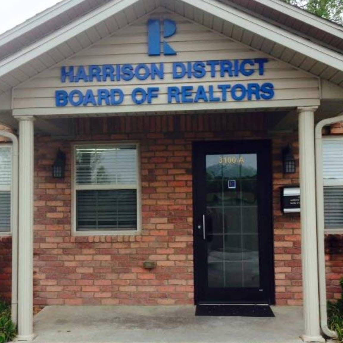 Harrison District Board of Realtors building with blue lettering, brick exterior, and black door.