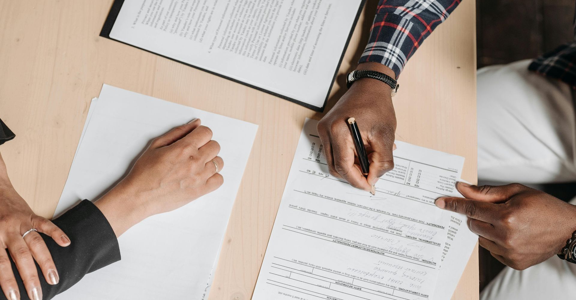 People at a table reviewing and signing paperwork, possibly a contract.