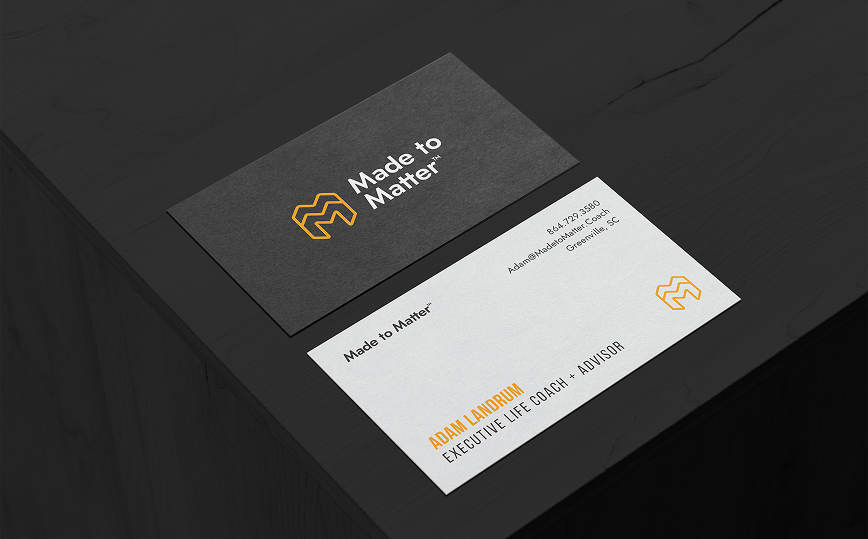 Two business cards on a black surface. One with a logo, the other with text and a logo.