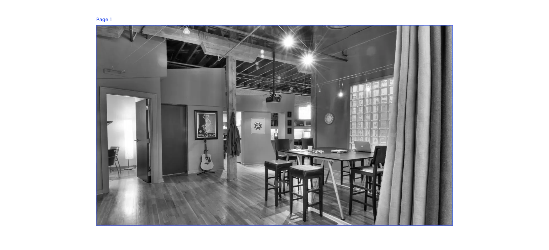 A grayscale photo of an interior space with a bar area, high stools, and art on the walls.