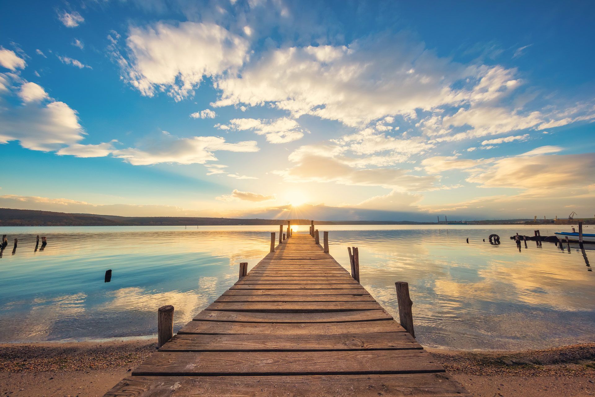 A wooden pier leading into a lake at sunset.