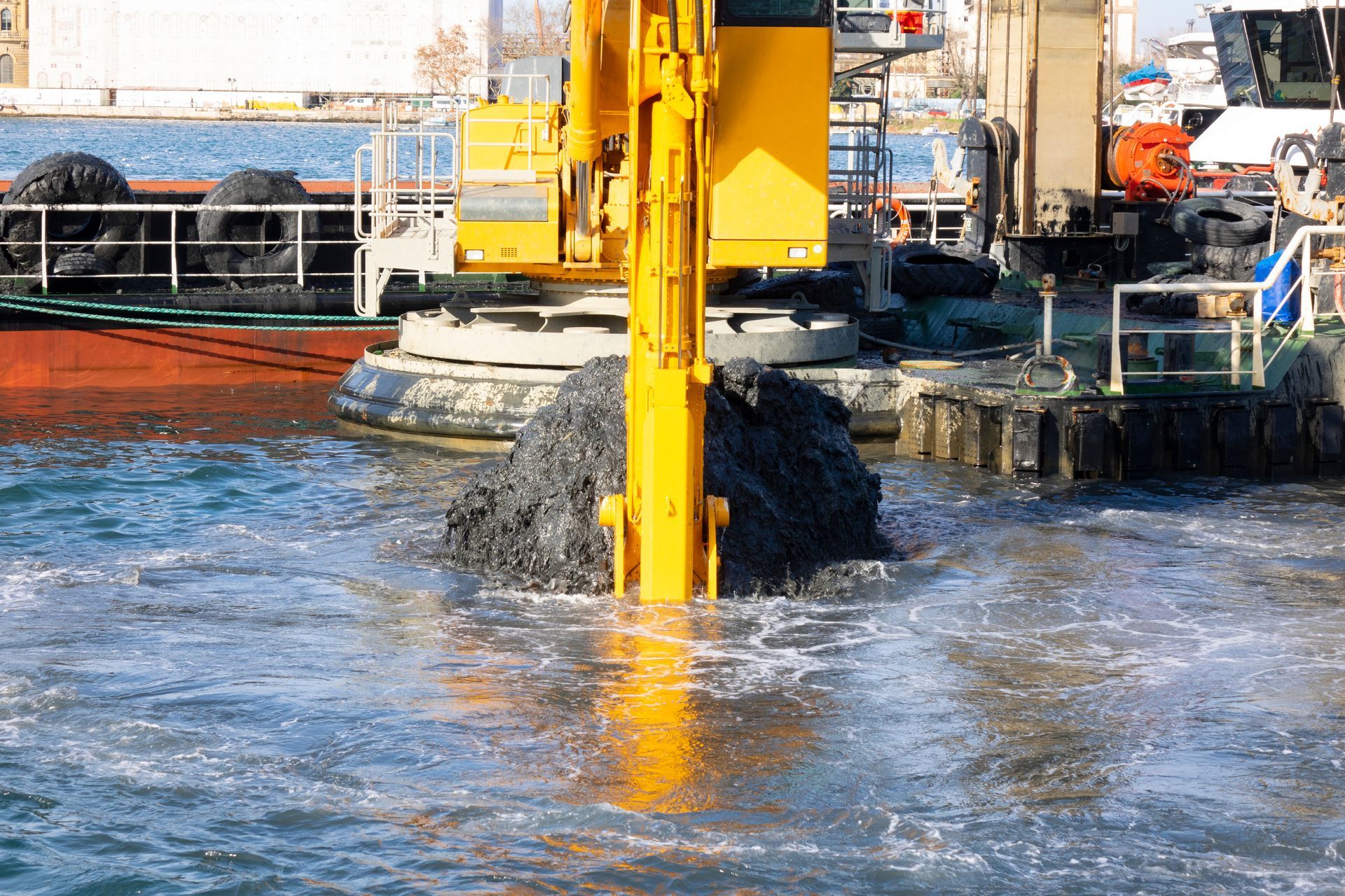 A yellow excavator is digging a hole in the water.