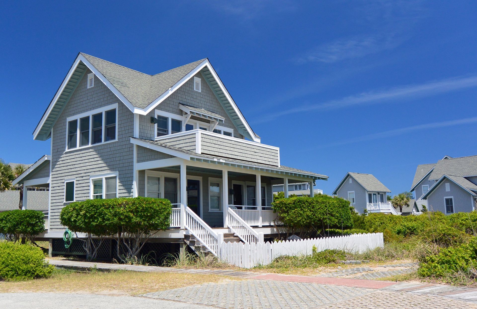 A house with a large porch and a blue sky in the background