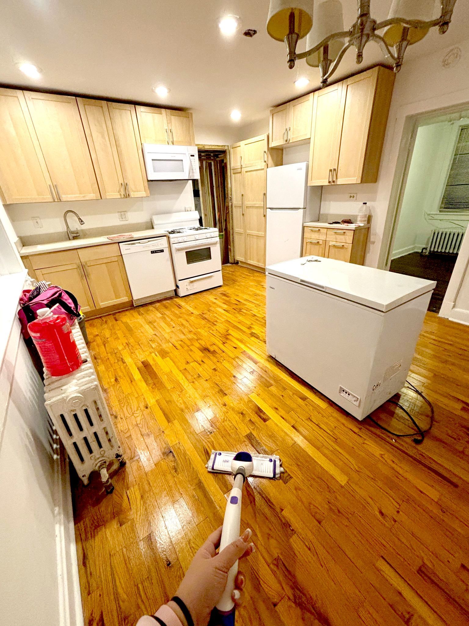 A person is cleaning a kitchen floor with a mop
