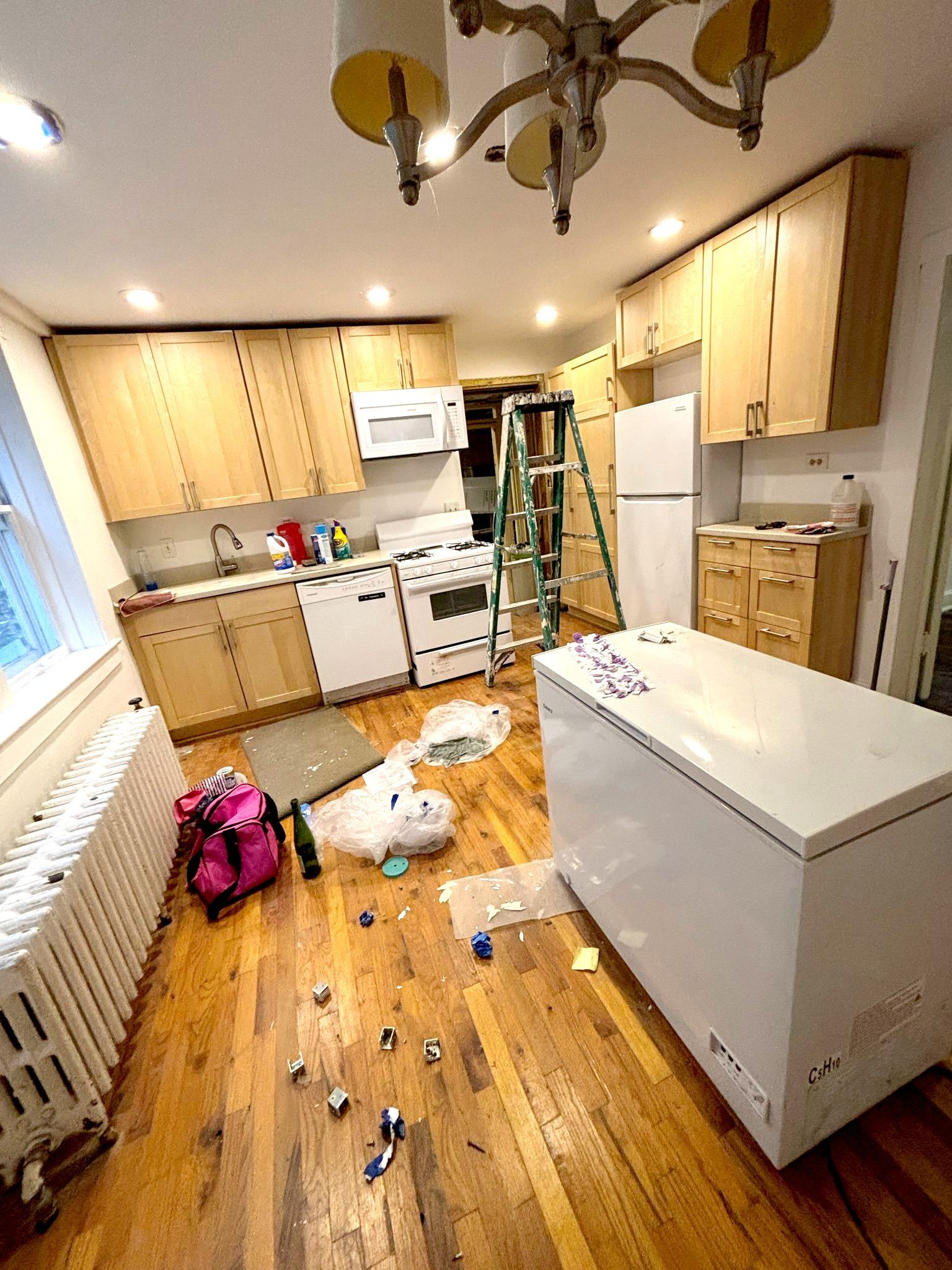 A kitchen with a ladder and a freezer in it