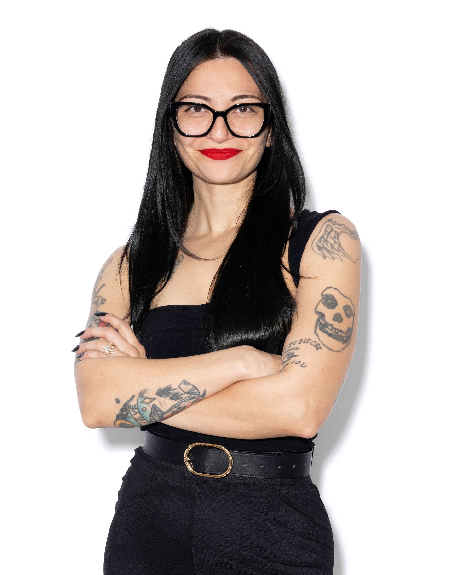 Woman with purple and pink hair, glasses, and a black shirt smiling in a library.