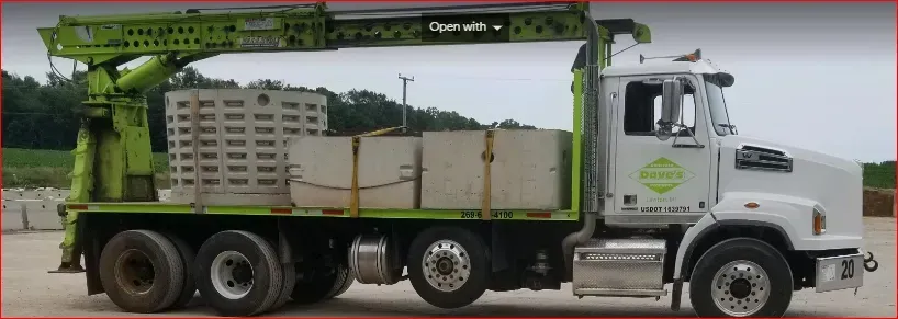 A green crane truck carrying concrete blocks.