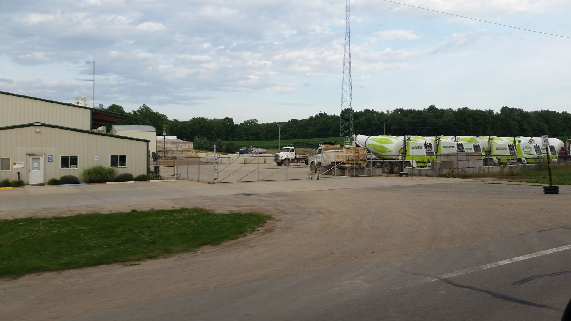 Exterior shot of a facility with trucks, a loading area, and a building on a cloudy day.