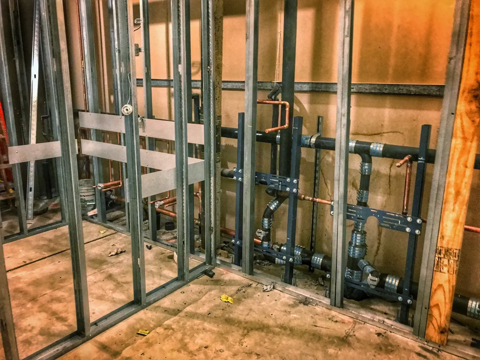 A room under construction with pipes coming out of the wall.