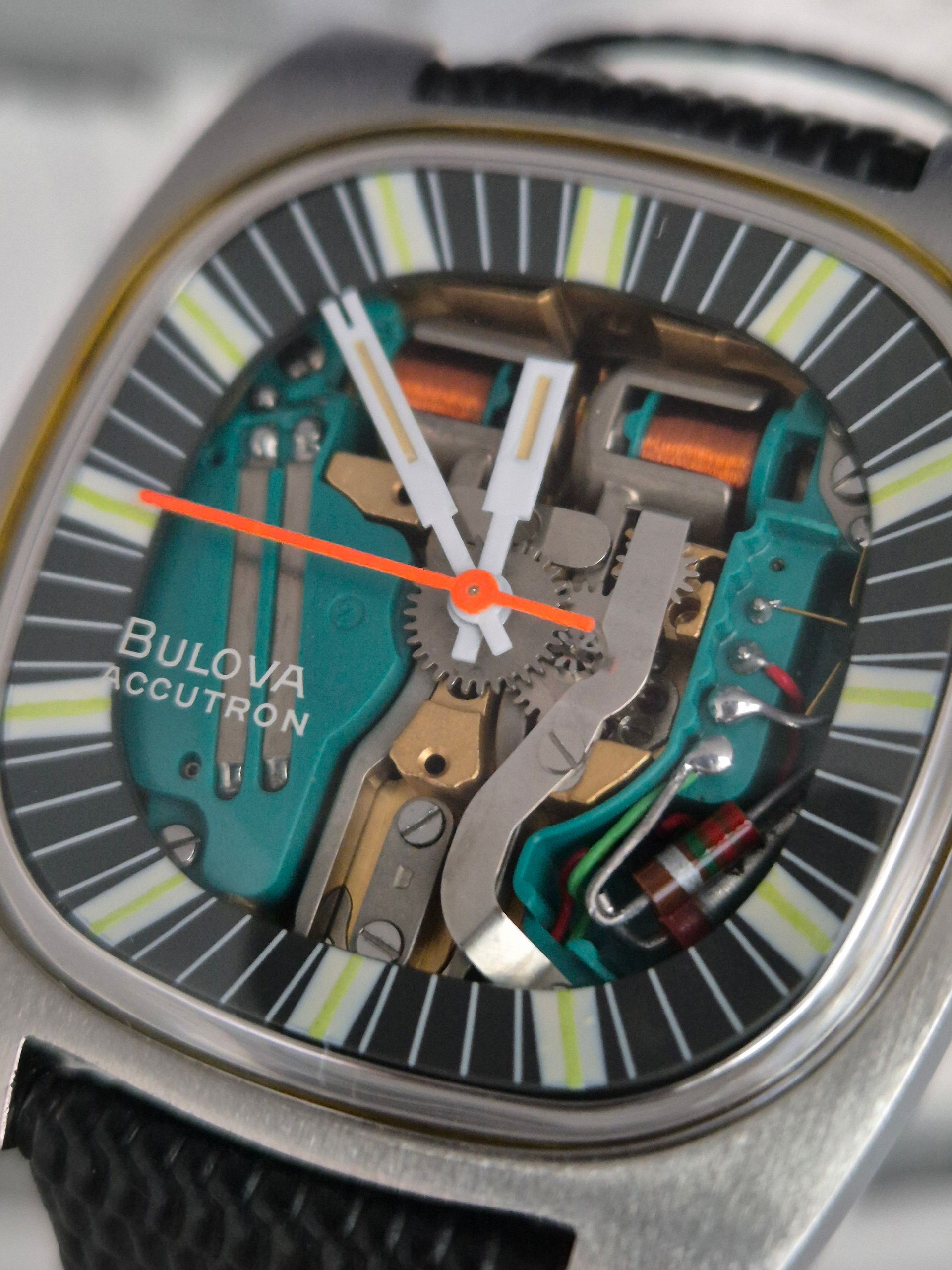 Bulova Accutron watch with open dial, revealing internal components and orange second hand.