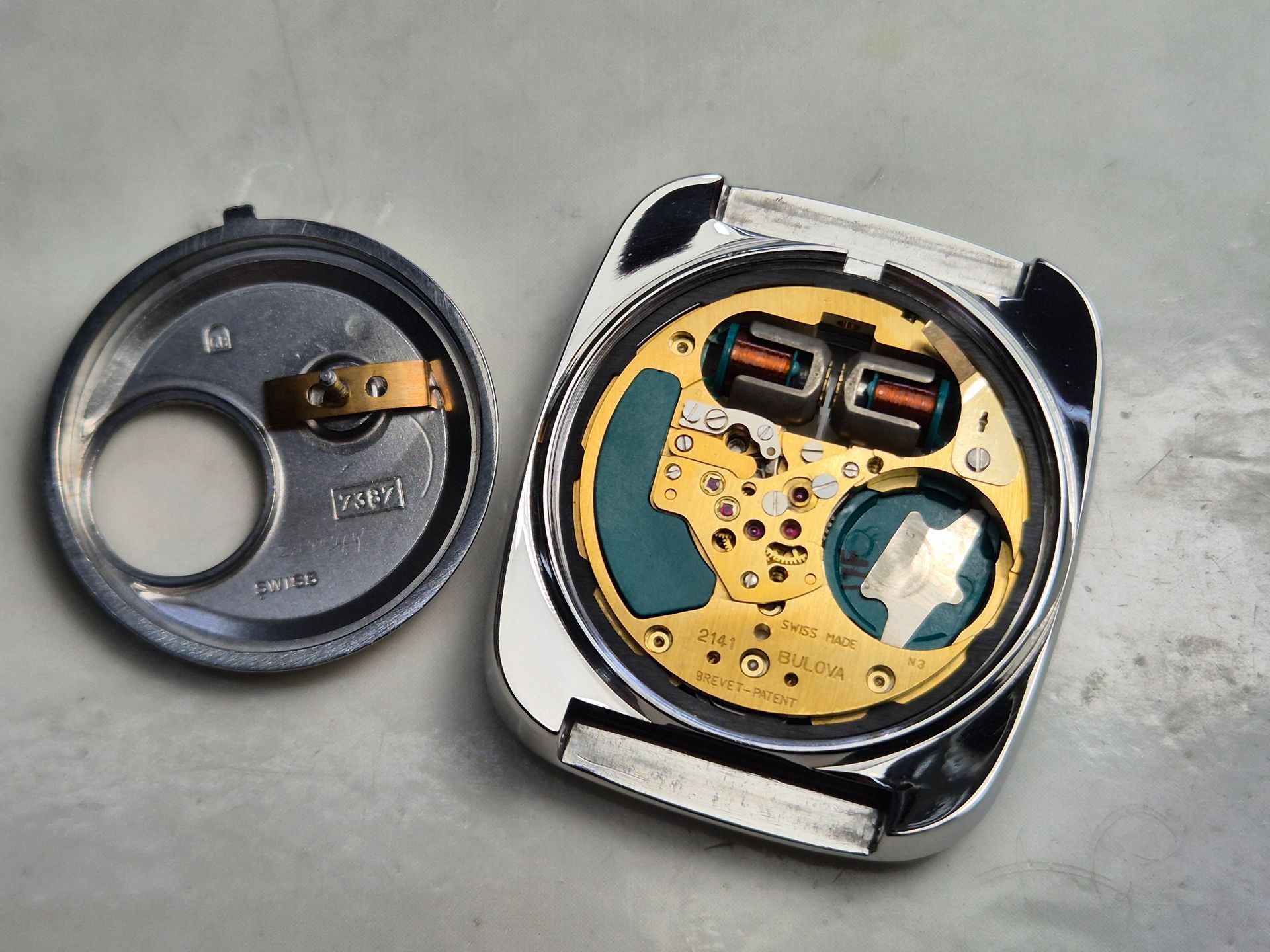 Open watch with movement exposed, revealing internal components and back cover.