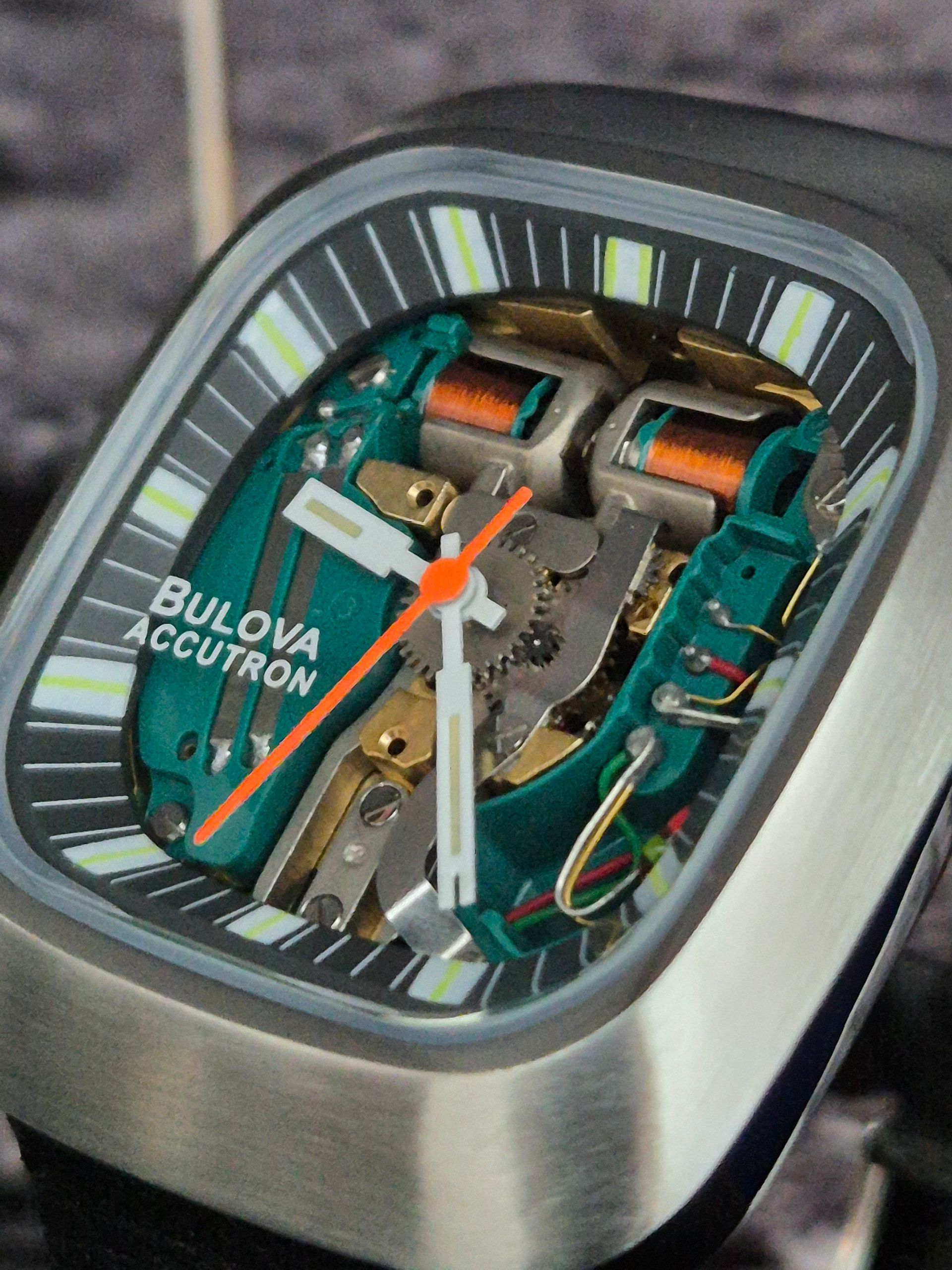 Close-up of a Bulova Accutron watch with an open face, showcasing the internal mechanism in green and gold.