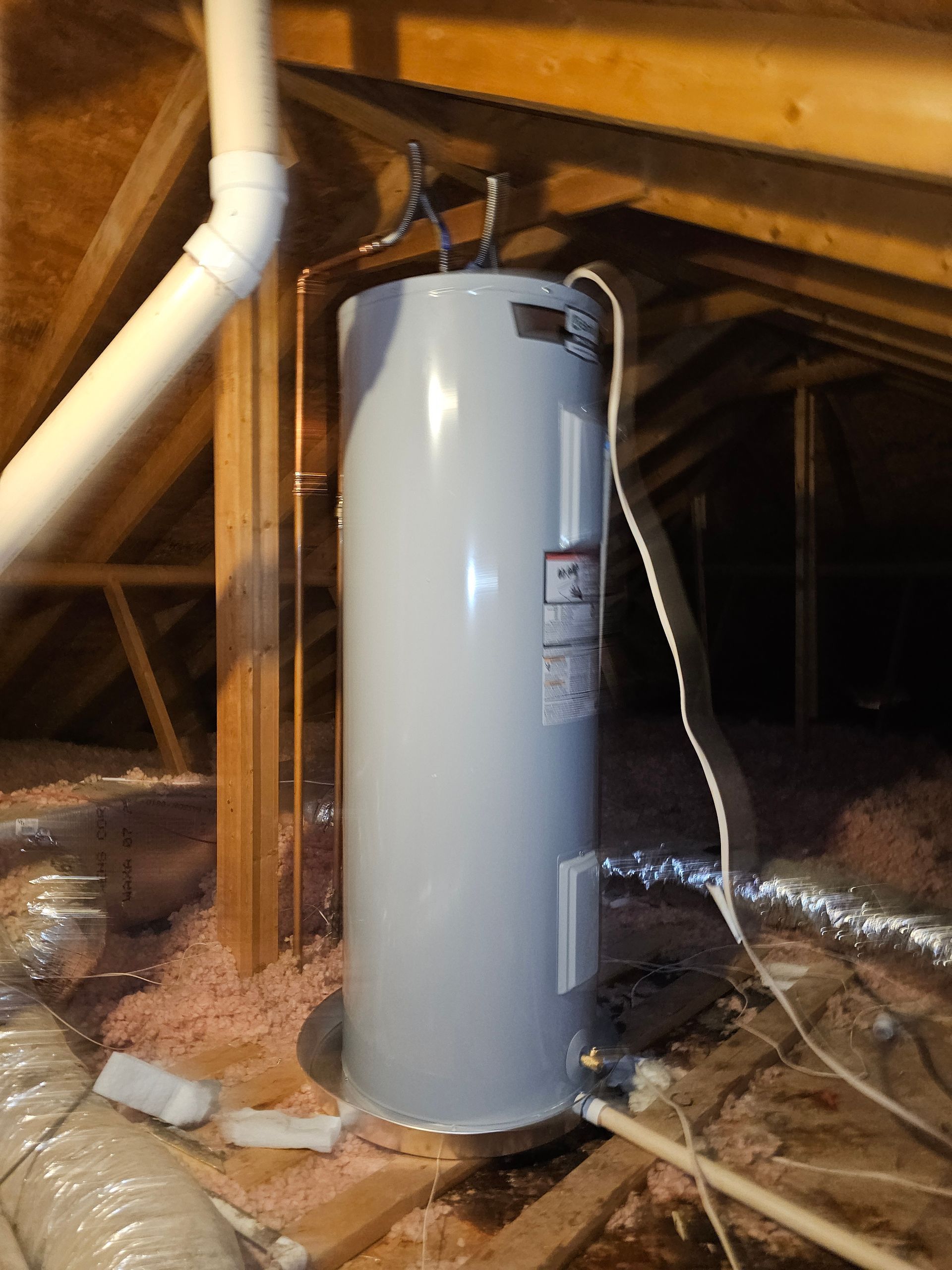 a white water heater is in the attic of a house