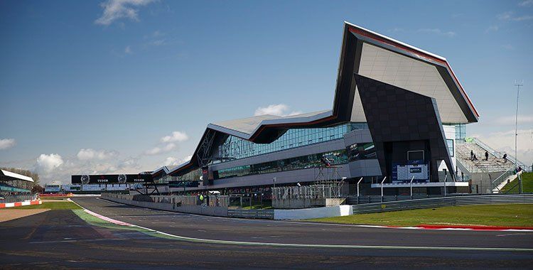 Racebaan met een modern, hoekig gebouw, waarschijnlijk een verkeerstoren, onder een blauwe lucht.