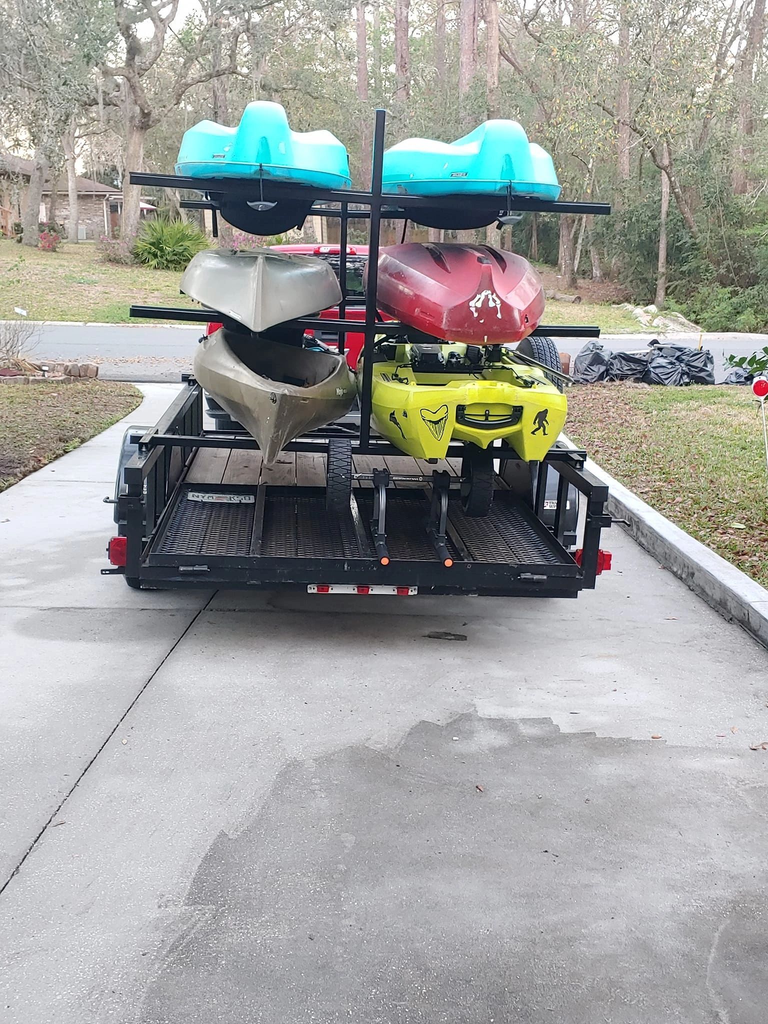 A trailer with kayaks on it is parked on the side of the road.