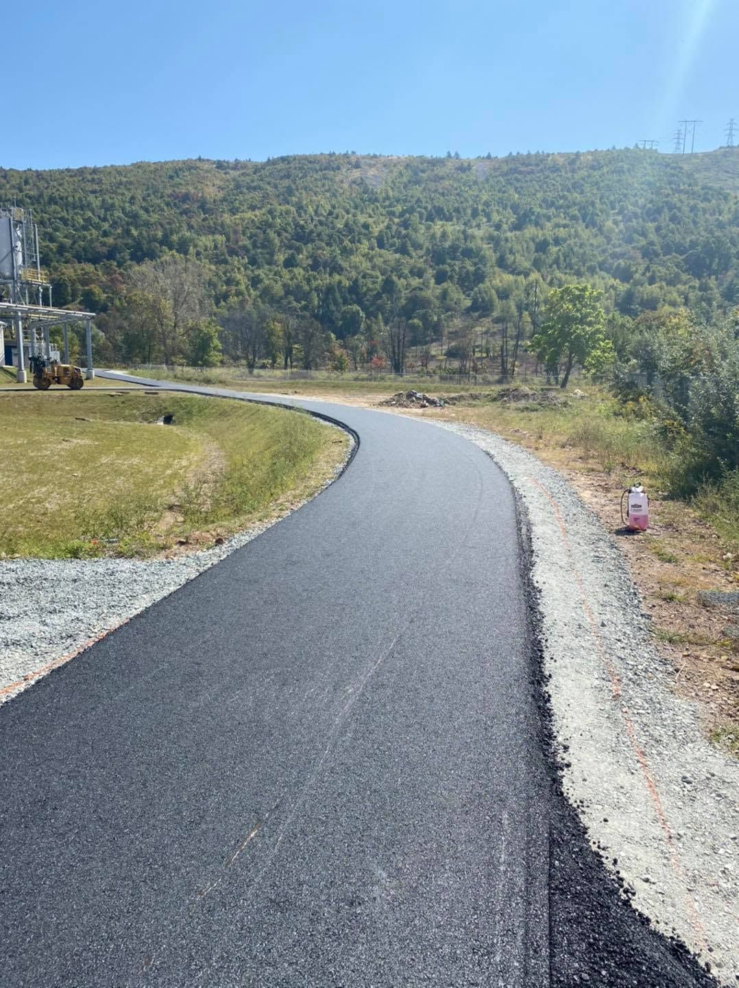 Paved winding path through grassy hillside under a clear blue sky