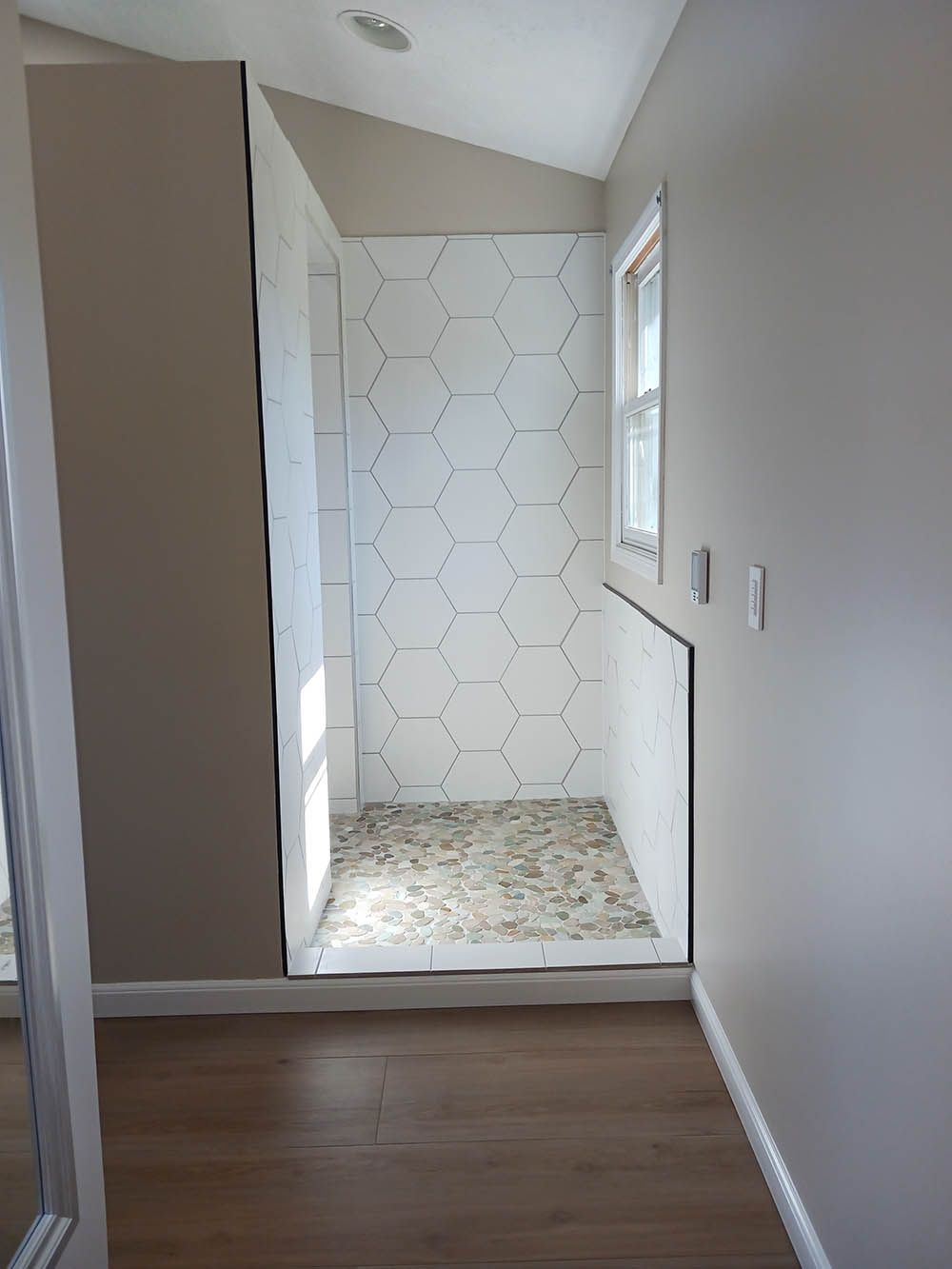 A bathroom with a walk in shower and a window.