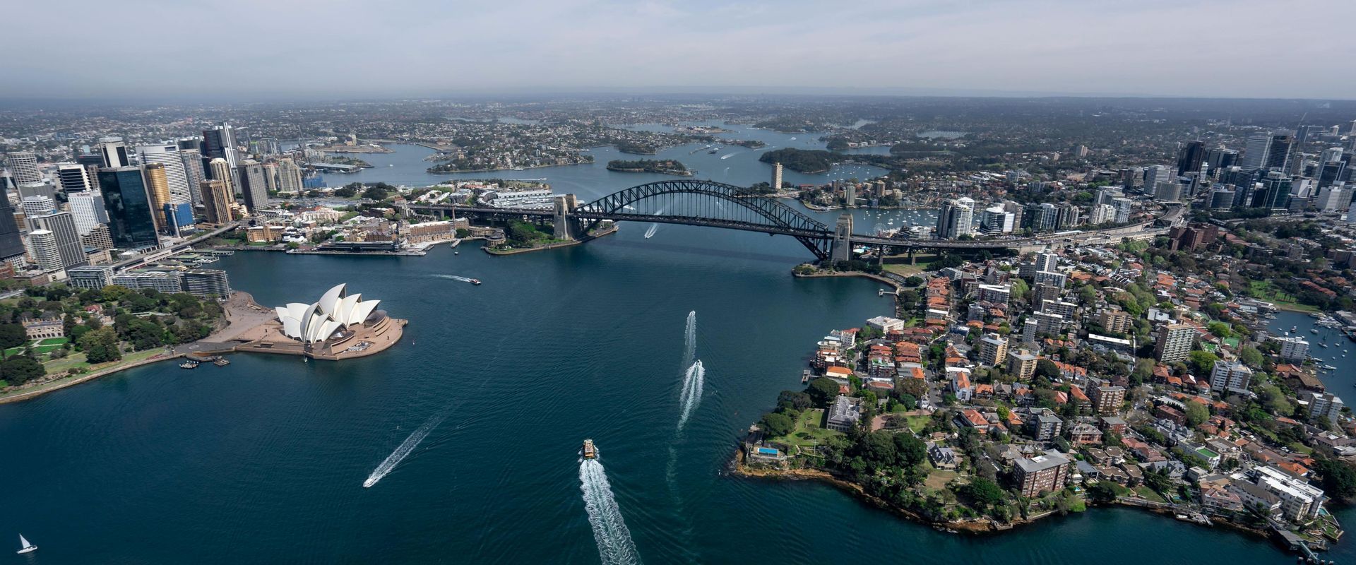 Aerial view of Sydney Harbour with the Opera House, Harbour Bridge, boats, and waterfront cityscape