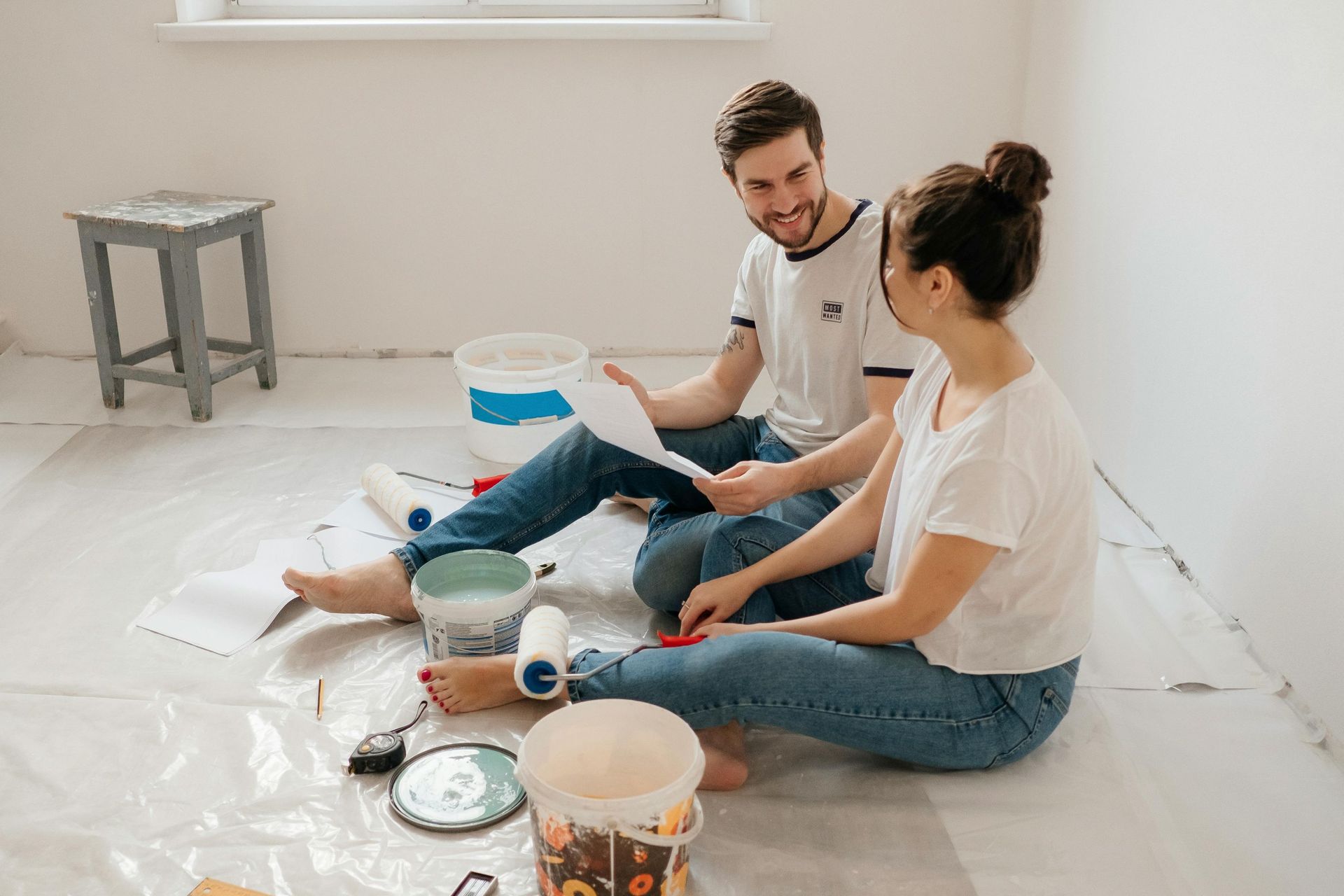 A couple on the floor surrounded with house painting materials.