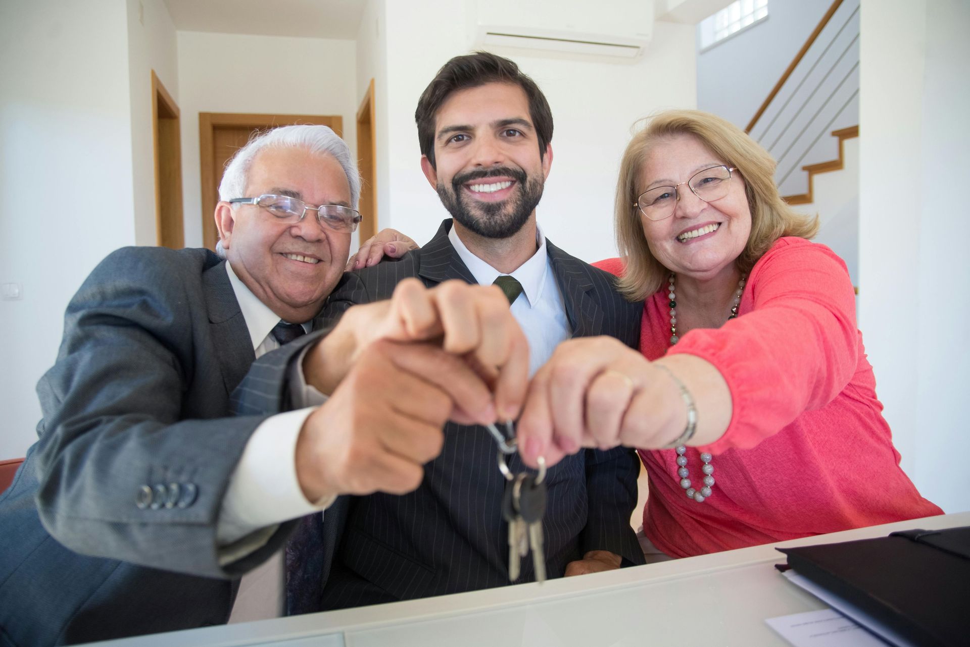 Three people holding up a house key together.