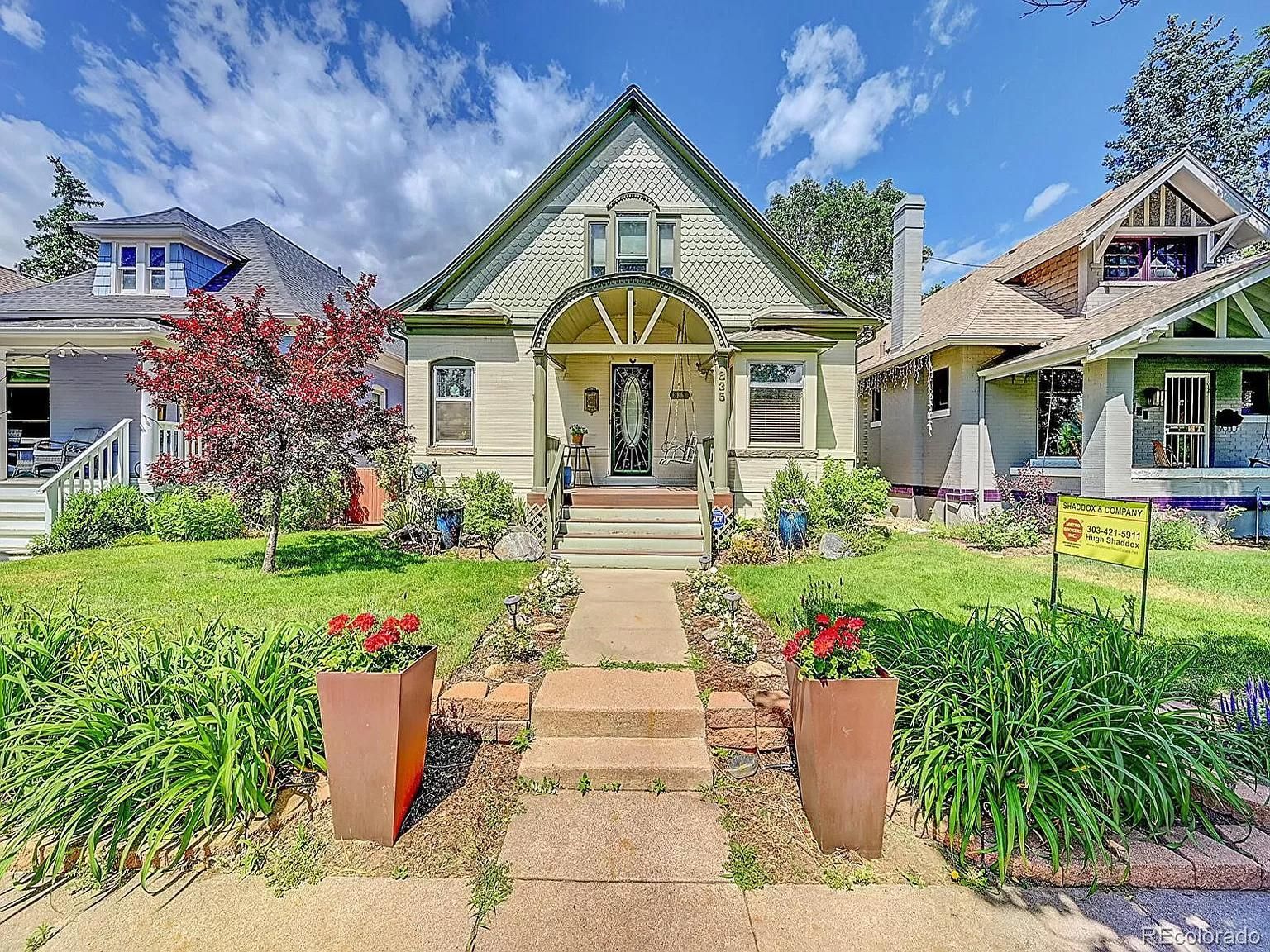 A house with a lot of flowers in front of it is for sale.