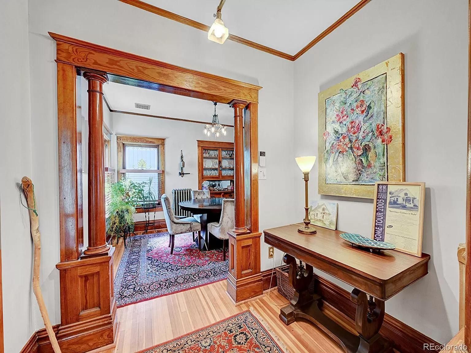 A dining room with a table and chairs and a painting on the wall.