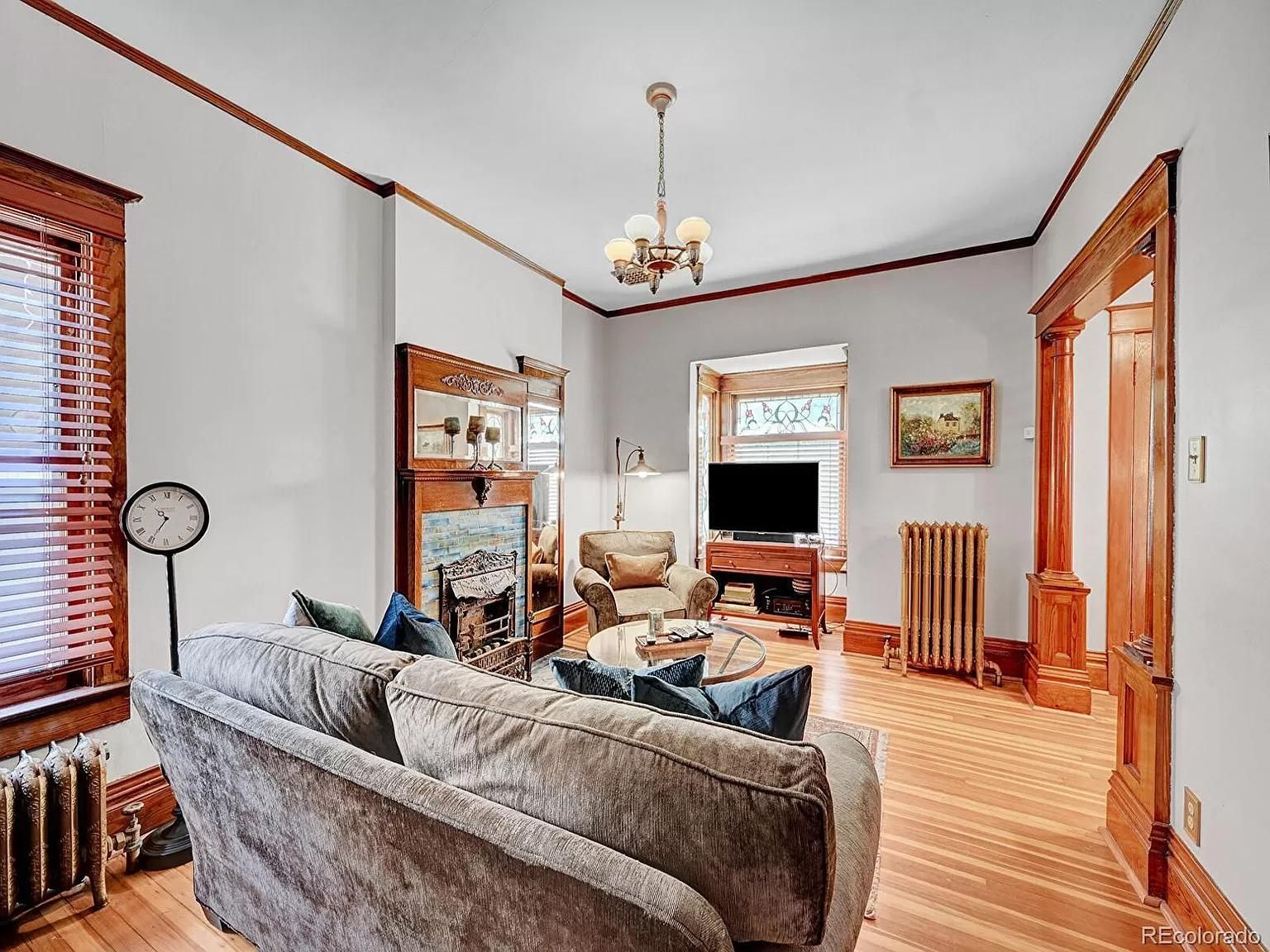 A living room with a couch , chairs , television and fireplace.