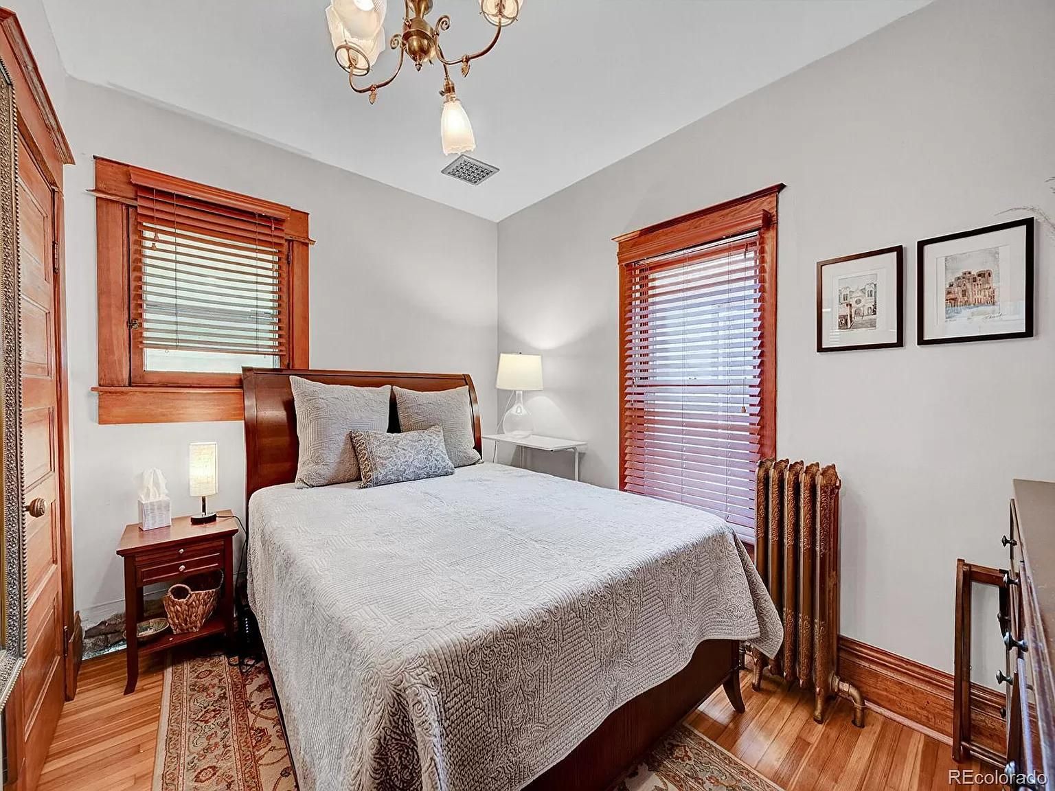 A bedroom with a bed , nightstand , lamp and window.